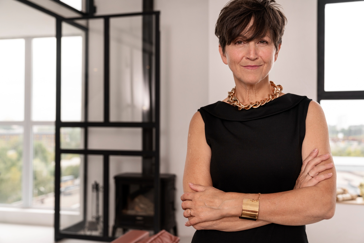 Moda feminina 40 anos ou mais, com mulher elegante em vestido preto e acessórios dourados, transmitindo confiança e sofisticação.